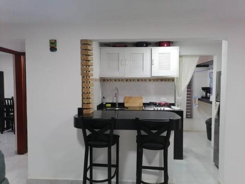 una cocina con mesa negra y 2 sillas negras en Departamento Centro Cancún SM 29, en Cancún