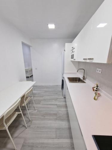 a kitchen with white counters and a sink and tables at GUANARTEME 33 in Las Palmas de Gran Canaria