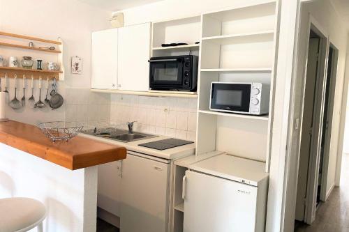 a small kitchen with a sink and a microwave at Charming cocoon by the sea in Pornichet