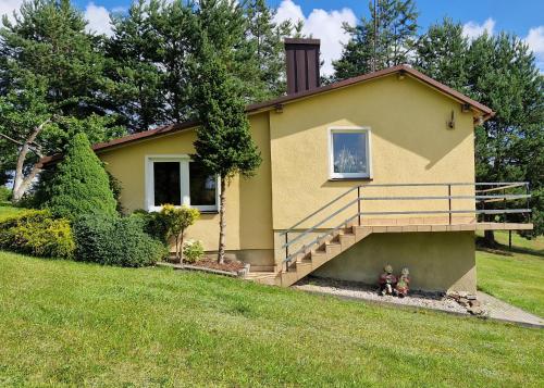 una pequeña casa amarilla con dos figuras delante de ella en Domek Karłowo u Eli en Sierakowice