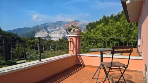 a balcony with a table and chairs and a view of mountains at Il Nido Del Cuculo in Carrara