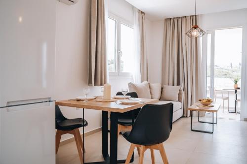 een keuken en een woonkamer met een tafel en stoelen bij Grand White Apartments in Agios Ioannis