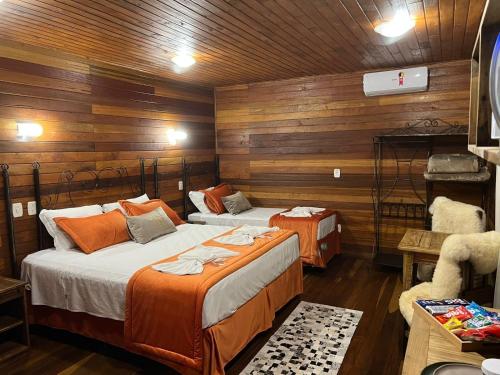two beds in a room with wooden walls at Hotel Cabanas Glamour in Gramado