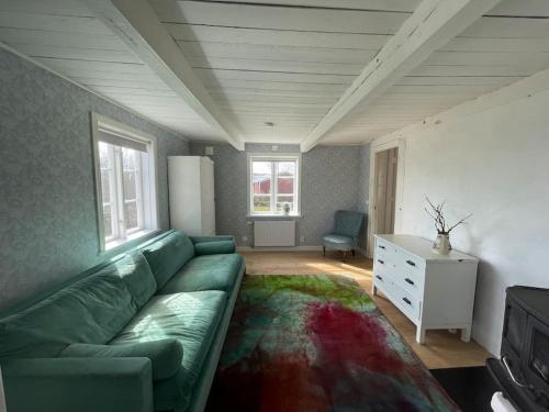 a living room with a green couch and a table at Stort semesterhus med sol in Båstad