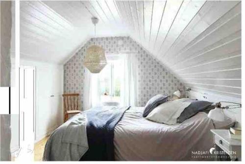 a bedroom with a bed with a white ceiling at Stort semesterhus med sol in Båstad