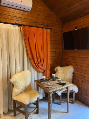 a room with a table and two chairs and a tv at Hotel Cabanas Glamour in Gramado