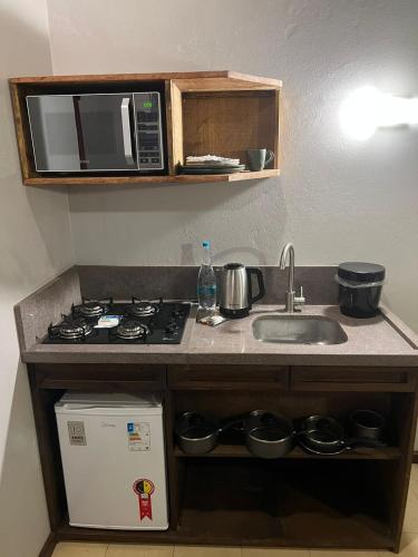 a kitchen counter with a sink and a microwave at Hotel Cabanas Glamour in Gramado