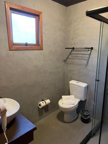 a bathroom with a toilet and a sink and a window at Hotel Cabanas Glamour in Gramado