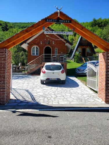 a white car parked in front of a garage at Vilat Pllumaj in Gropat e Selcës