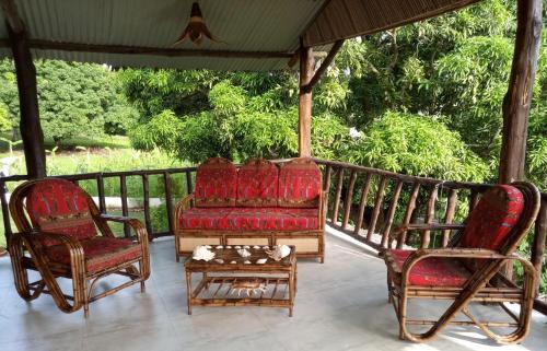 two chairs and a couch on a porch at L'OUSTAL DE NOSY BE in Nosy Be