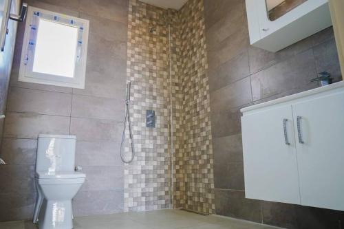 ein Bad mit einer Dusche, einem WC und einem Fenster in der Unterkunft Apt 5min de la zone touristique in Hammamet