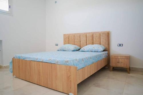 Un dormitorio con una gran cama de madera con sábanas azules en Apt 5min de la zone touristique en Hammamet