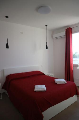 a bedroom with a red bed with two towels on it at L'Atelier di Vittoria in Carini