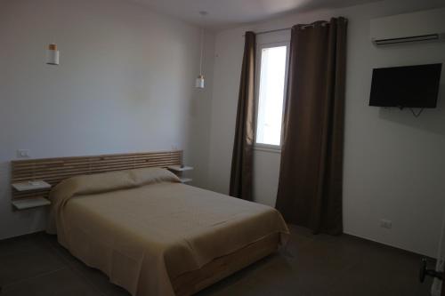 a bedroom with a bed and a window and a television at L'Atelier di Vittoria in Carini