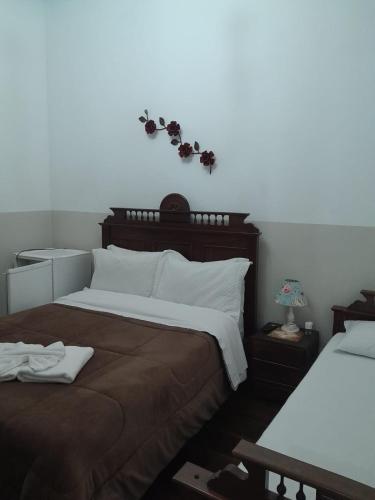 a bedroom with two beds and a white wall at POUSADA PARLATORIUM in Tiradentes