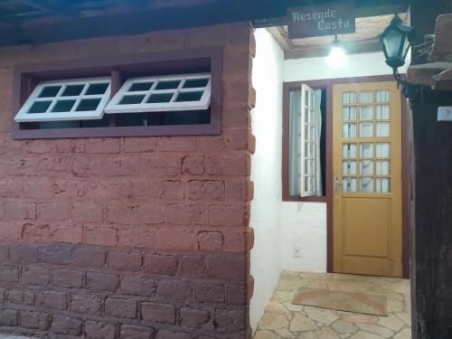 a brick wall with a window and a door at POUSADA PARLATORIUM in Tiradentes