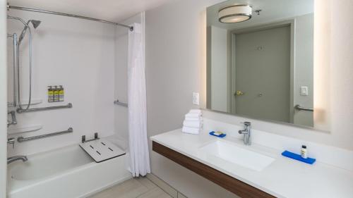 a bathroom with a sink and a tub and a mirror at Holiday Inn Express & Suites Dinuba West by IHG in Dinuba