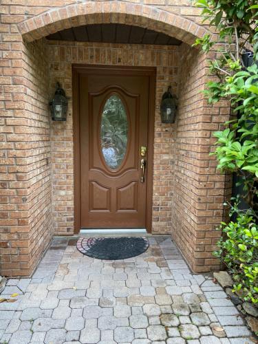 a brown door in a brick building with a stone walkway at Shared Awesome Villa in Melbourne