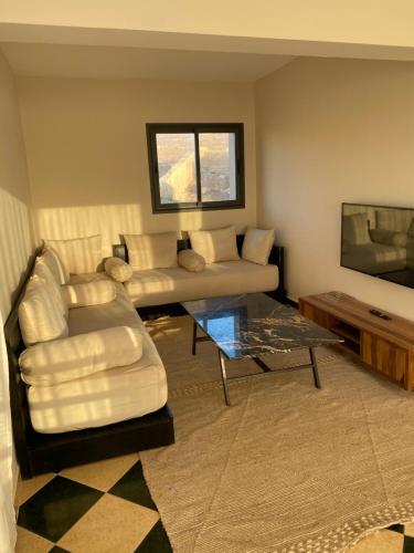 een woonkamer met een bank, een tafel en een tv bij cap beddouza in Meddouza