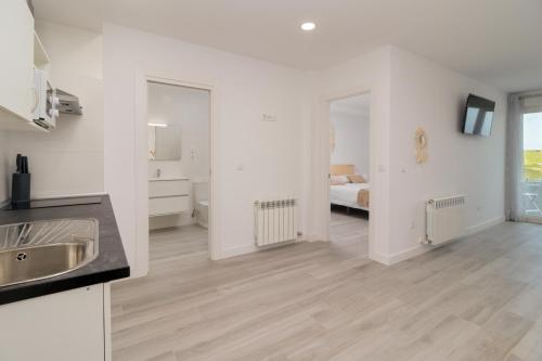 a white apartment with a kitchen and a bedroom at REFUGIO DEL PESCADOR Apartamento Maruca in Santander