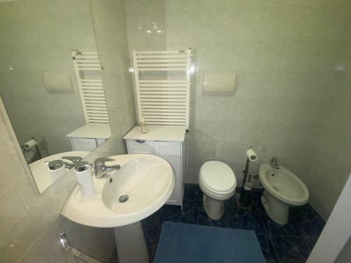 Baño blanco con lavabo y aseo en APPARTAMENTO SUL MARE KATE, en Génova