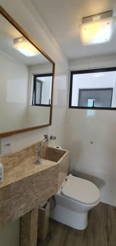 a bathroom with a sink and a toilet and a mirror at Apartamento TOP 2 quartos e 2 vagas garagem in Balneário Camboriú