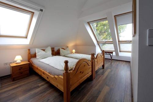 a bedroom with a wooden bed and two windows at Haus Müritz, FeWo 15 Seeadler in Zielow