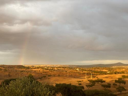 a rainbow in the sky over a field at Herdade da Moringa in Corte do Pinto