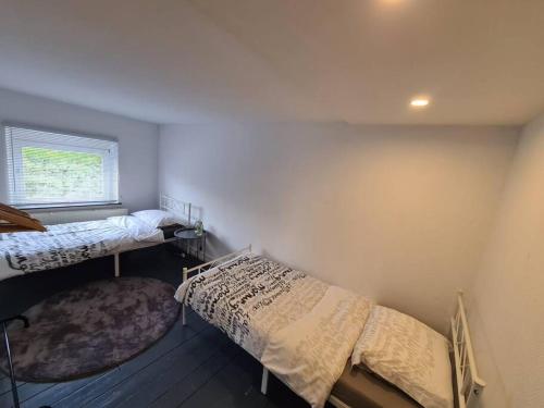 2 camas en una habitación con ventana y alfombra en Duplex dans le centre d'Heusy, en Verviers