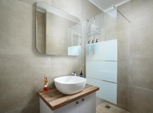 een badkamer met een witte wastafel en een spiegel bij The H Experience - Urban 2BD Rooftop Athens Center in Athene