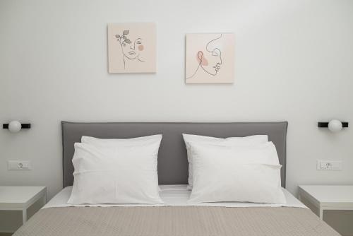 ein Bett mit weißen Kissen und zwei Bildern an der Wand in der Unterkunft The H Experience - Eclectic spacious apartment near Venetian Castle - 2 in Iraklio