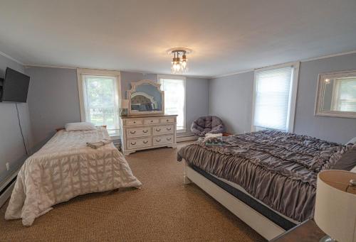 a bedroom with two beds and a dresser and a mirror at The Kelly House - 4 BR Historic Lodge - Downtown in Ellicottville