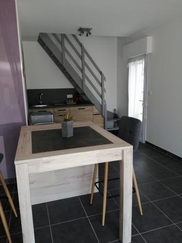 ein Esszimmer mit einem Tisch und einer Treppe in der Unterkunft Appartement 2-3 personnes sur la côte d'Emeraude in Saint-Cast-le-Guildo