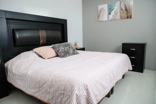 a bed with a black headboard and a pink pillow at Casa Vainilla 3 in Oaxaca City