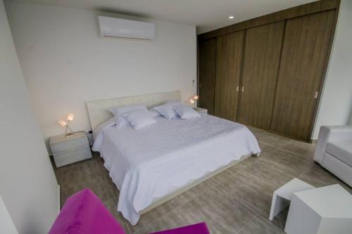 ein Schlafzimmer mit einem großen weißen Bett mit lila Kissen in der Unterkunft Hermoso y Amplio Apartamento Frente al Mar. in Cartagena de Indias