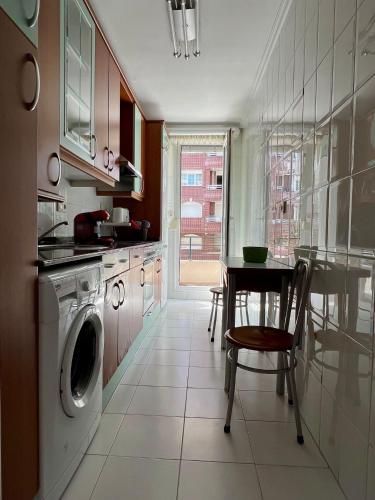 a kitchen with a table and a washing machine at Apto Anita 5 ' playa Brazomar in Castro-Urdiales
