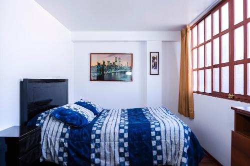 um quarto com uma cama com um edredão azul e uma janela em Casa de Laura em Cusco