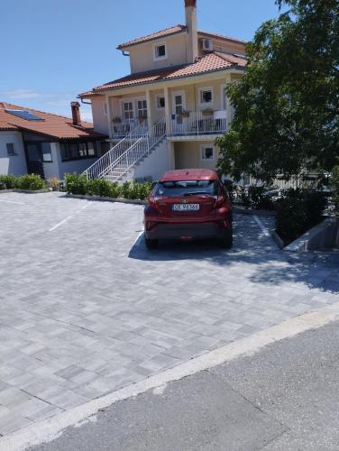 a red car parked in a parking lot in front of a house at Apartments Kolmanic, sea view, free privat parking in Ičići