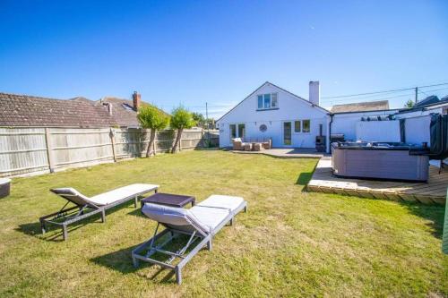 a backyard with two chairs and a grill and a house at Bancroft - Camber Sands - East Sussex in Camber