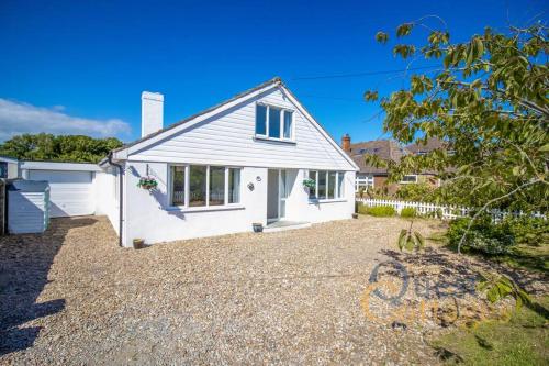 um chalé branco com uma entrada de cascalho em Bancroft - Camber Sands - East Sussex em Camber