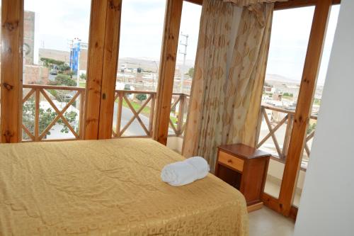 a bedroom with a bed and a large window at Hotel Los Flamencos in Paracas