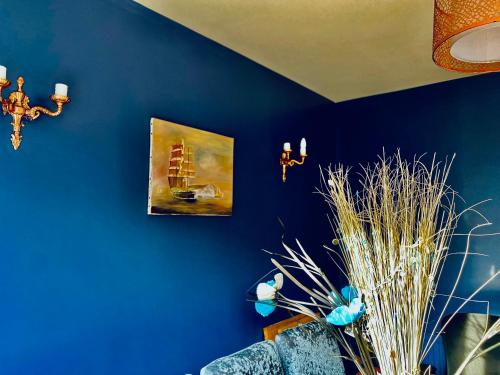 a room with a blue wall with a painting and a plant at The Grange in Admaston