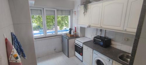 a kitchen with white cabinets and a washer and dryer at Aconchegante T3 em Telheiras in Lisbon