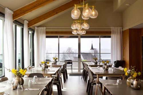 um restaurante com mesas e cadeiras e janelas grandes em Jelsa Hotell em Jelsa