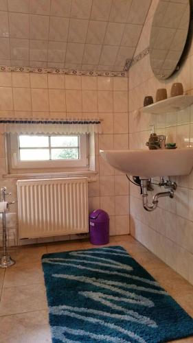 a bathroom with a sink and a mirror and a rug at Haus-Schiffer-Ferienwohnung-Finja in Rhauderfehn