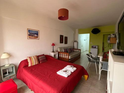 1 dormitorio con cama roja y sala de estar en DEPARTAMENTO PLAYA MIRAMAR en Miramar