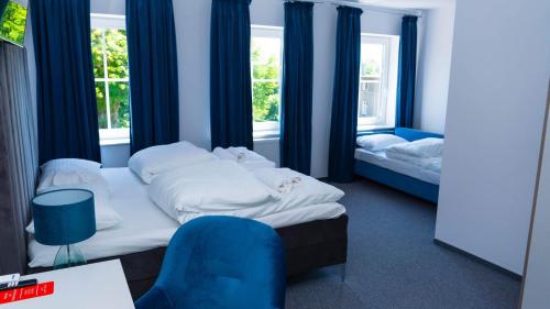 een slaapkamer met 2 bedden en een blauwe stoel bij Bon Żur in Brzeg