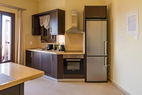 a kitchen with brown cabinets and a refrigerator at Theoxenia Kasos Luxury Apartments in Panayía