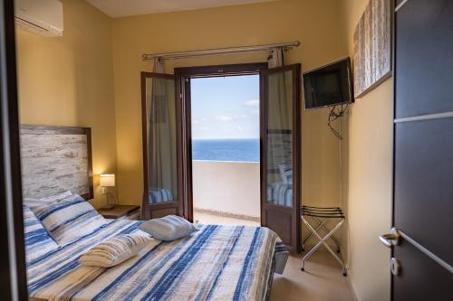 a bedroom with a bed with a view of the ocean at Theoxenia Kasos Luxury Apartments in Panayía