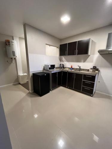a small kitchen with black and white cabinets and appliances at Apart JJ - Departamento céntrico - amueblado a estrenar in Paso de los Libres